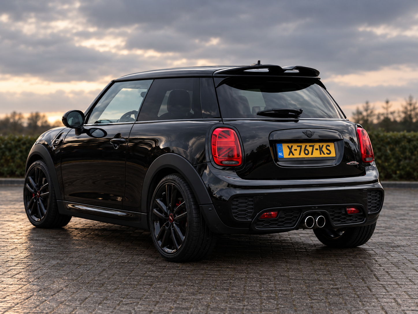 Zwarte Mini Cooper S hatchback bij zonsondergang
